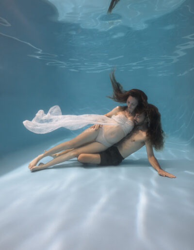A woman and husband during an underwater maternity photoshoot