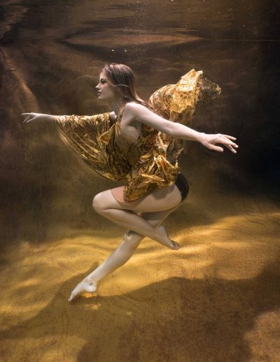 Underwater portrait of a woman in a pool with a gold Kate backdrop