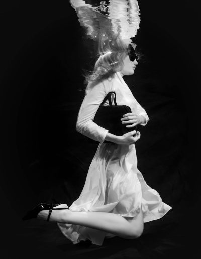 Underwater fashion photoshoot of a woman in a pool with a red Kate backdrop