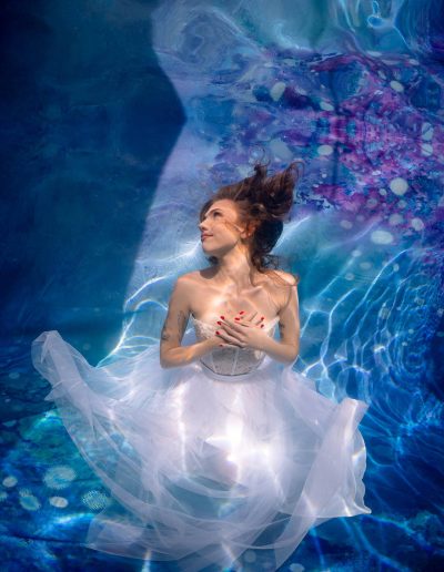 Underwater portrait of a woman in a pool with a blue Kate backdrop