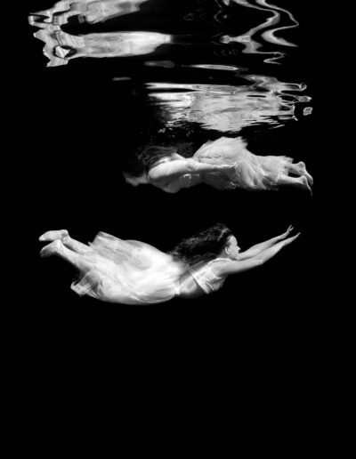 Underwater portrait of two sisters on a black background