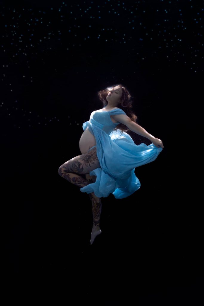 Expecting mother floating gracefully in blue dress during underwater photoshoot in Townsville