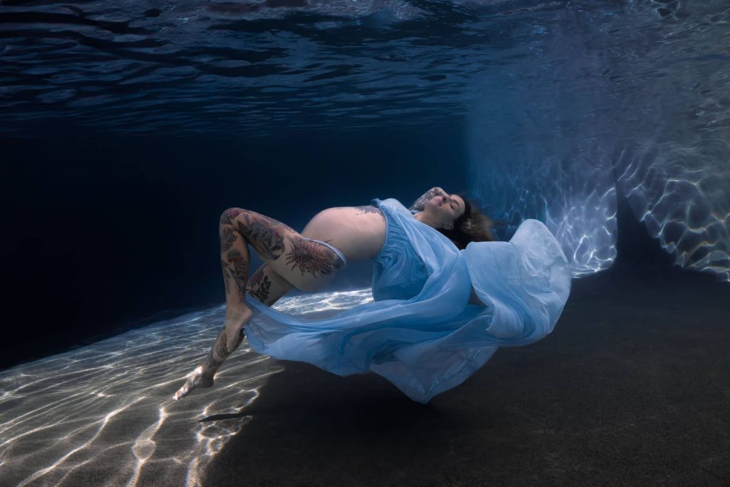 Pregnant woman in flowing blue dress during underwater maternity photoshoot in Cairns and Port Douglas